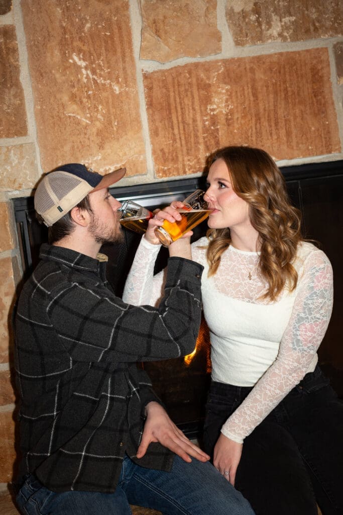 Criss cross drinking beers at Leinie Lodge engagement session in Chippewa Falls, Wisconsin. Photo by Spirited Sage Photography, an Eau Claire wedding photographer
