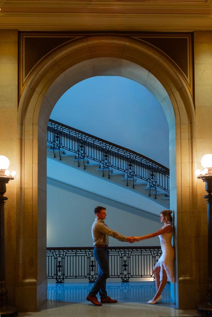 Archway shot of couple at their MN State Capitol engagement session by Maddie from Spirited Sage Photography, a true to color traditional wedding photographer in Western Wisconsin
