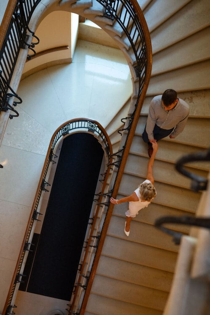 Overhead view of man and woman walking down steps at MN State Capitol for their St. Paul, MN engagement photos, by Maddie, a true color editorial wedding photographer based out of Wisconsin