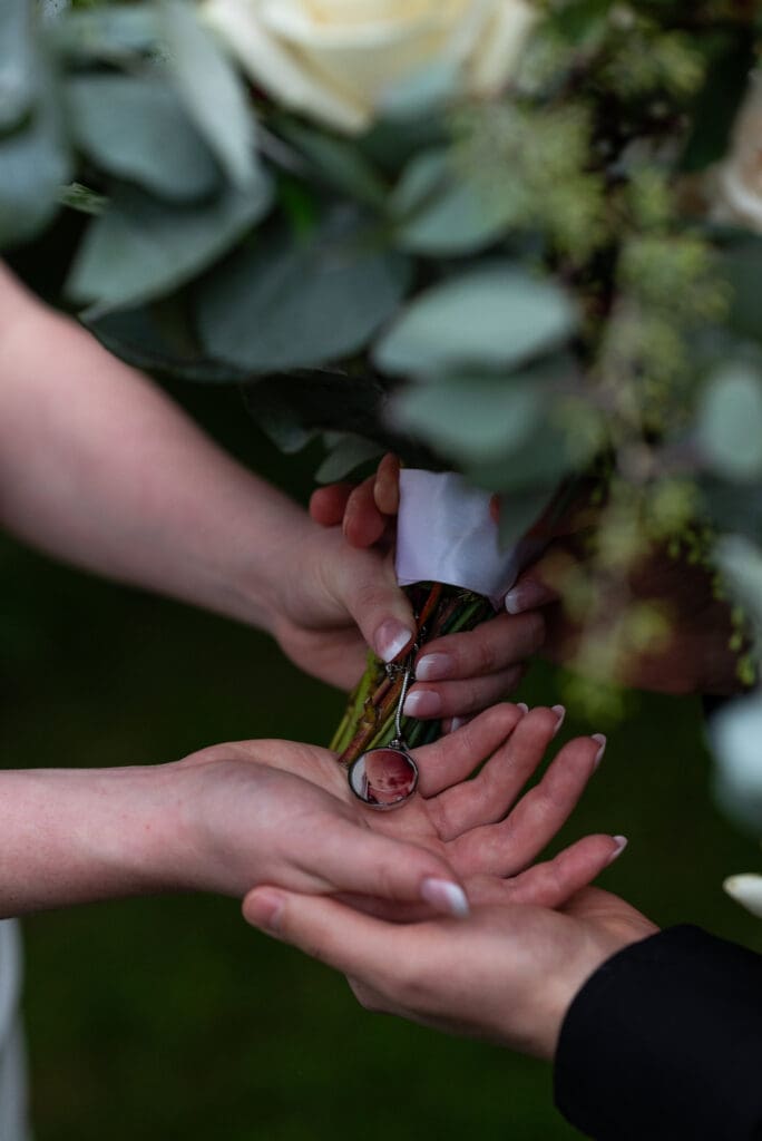 Meaningful charm on bridal bouquet showing their son they lost. true color documentary wedding photographer