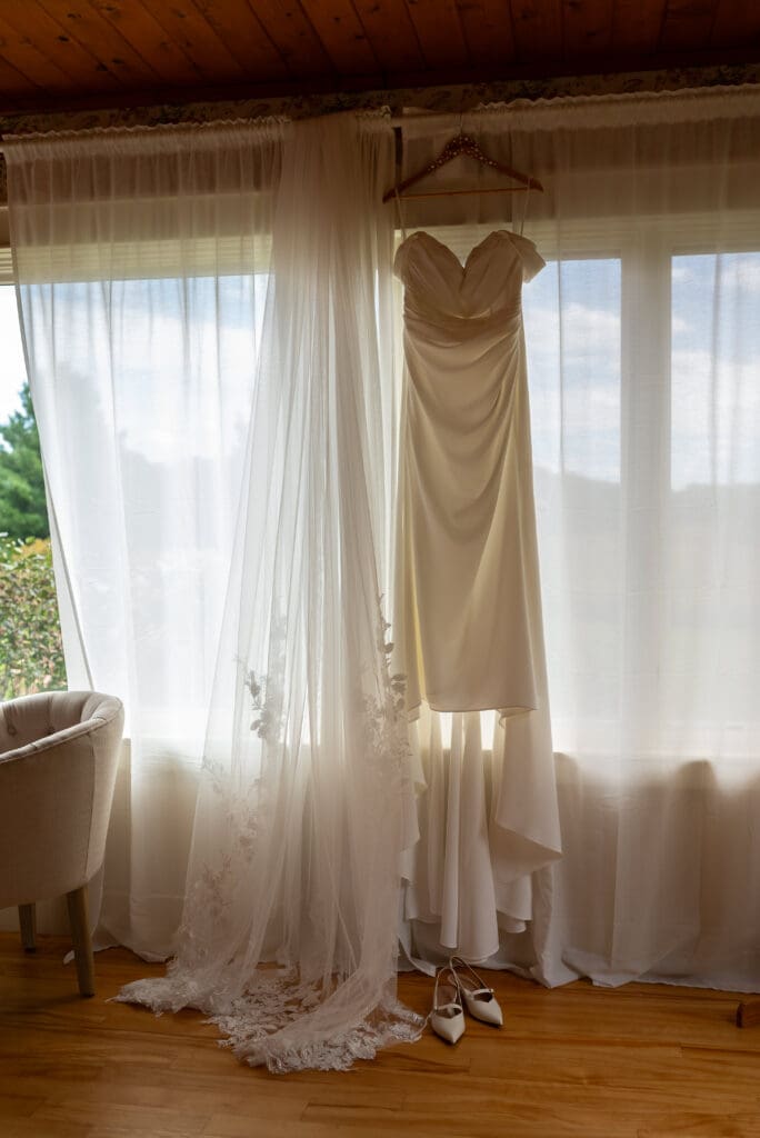 wedding dress hanging in front of window at La Crosse wedding venue Maidenwood Weddings + Events in Stockholm, Wisconsin. True to color wedding photographer. natural light wedding photographer La Crosse. La Crosse wedding photographer