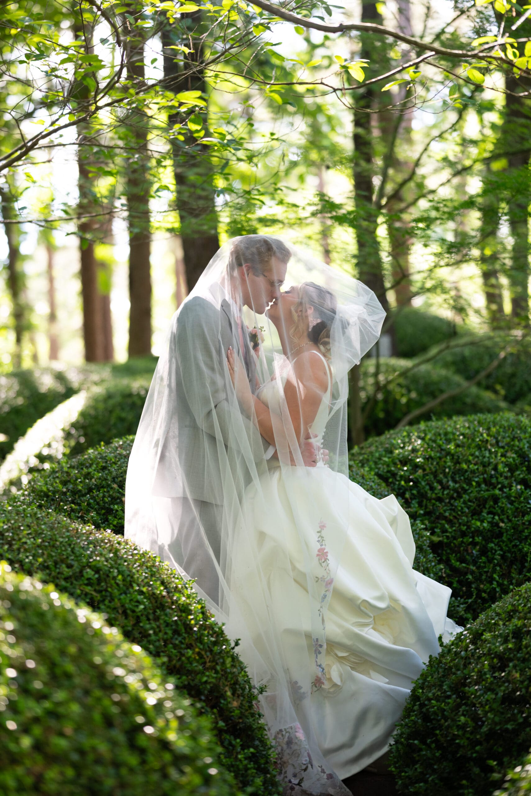 Bride and groom portrait under the veil surrounded by the shrubbery at Anthony Chapel in Hot Springs, AR