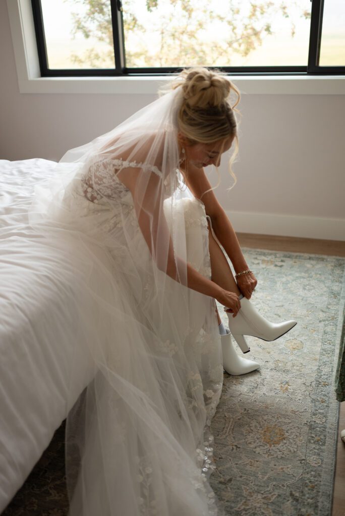 Bride putting her boots on for her western micro wedding in Montana AirBnB