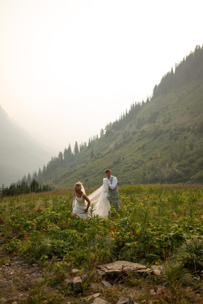 Bride and groom walking through wildflowers at glacier national park in Montana