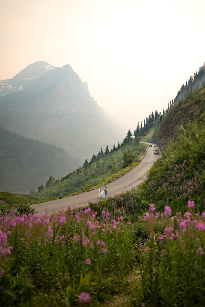 Very cool shot of bride and groom running across the road by the Weeping Wall at Glacier National Park for their wedding