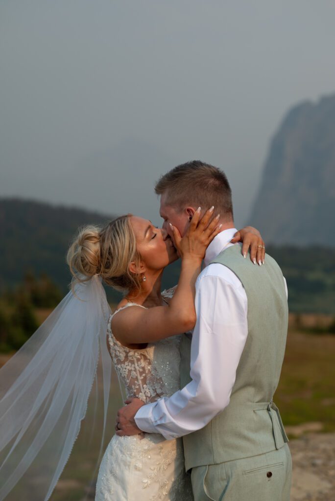 Bride and groom kissing at golden hour at Logan Pass in Glacier National Park, Montana