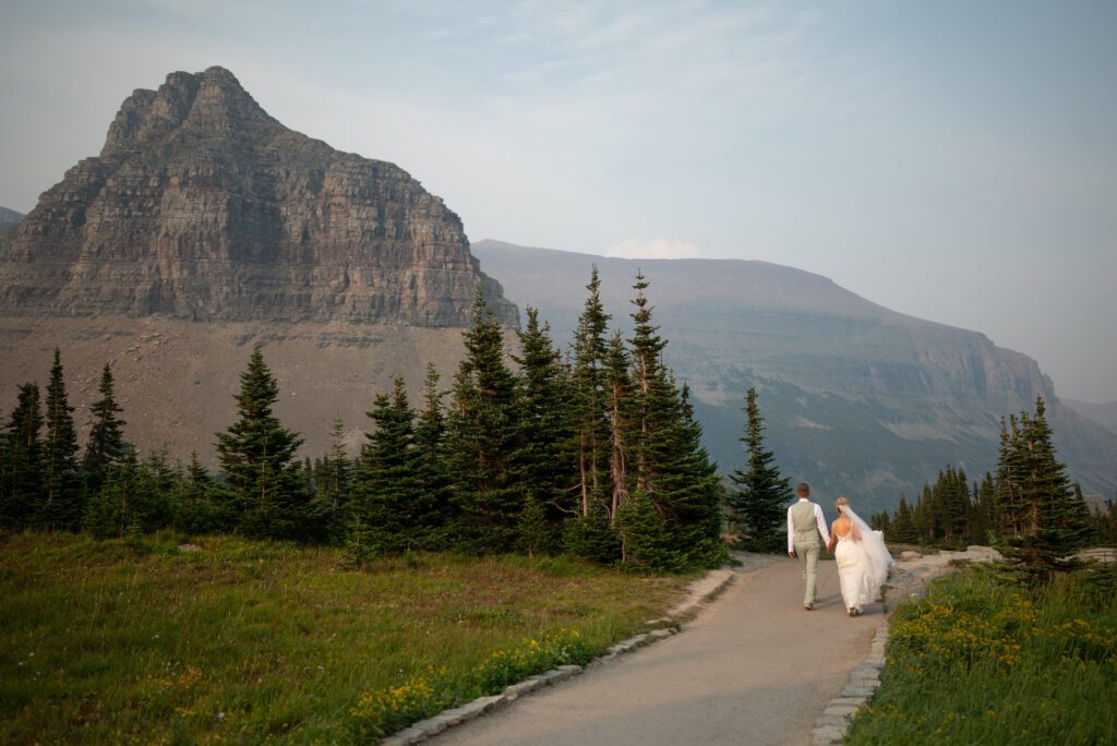Bride and groom walking along the trail of Hidden Lake Overlook at Logan Pass in Glacier National Park