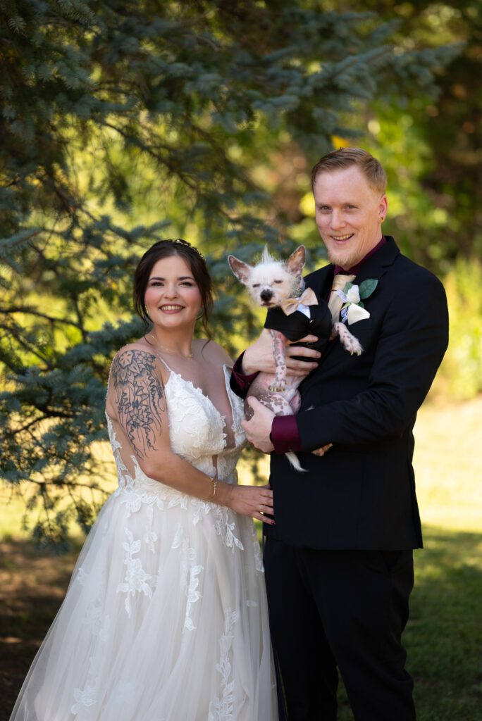 Bride and groom posing with their dog on their wedding day