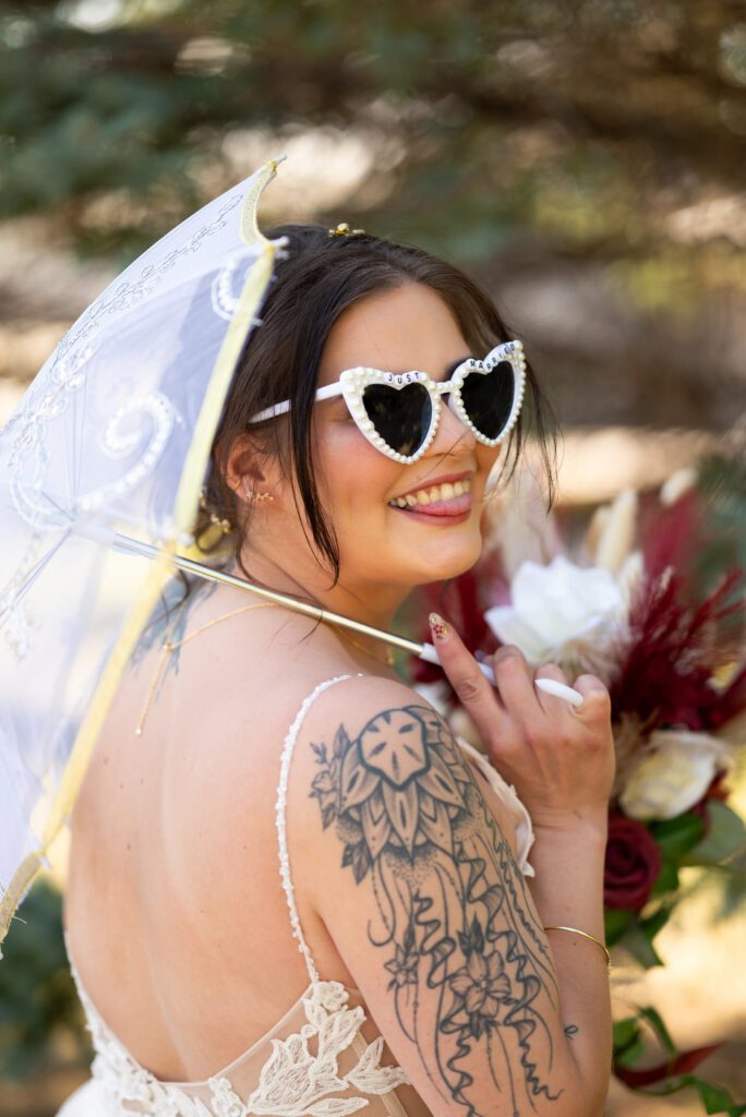 cool girl bride with parasol and beaded heart vintage sunglasses and tattoos
