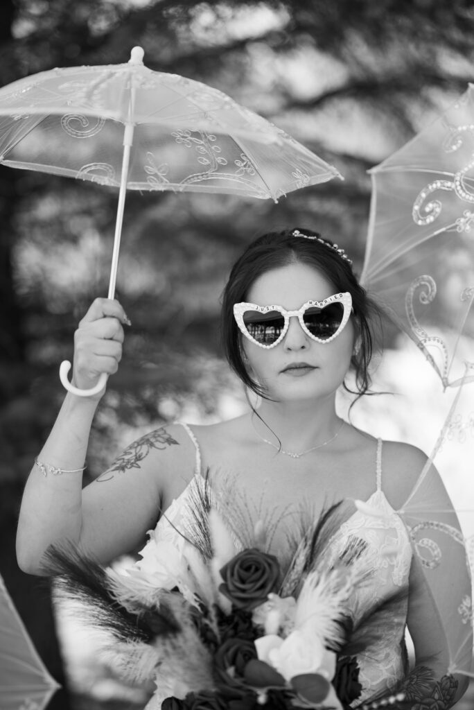 editorial wedding photographer in wisconsin captured cool girl image if tattooed bride with parasol and vintage inspired bridal sunglasses