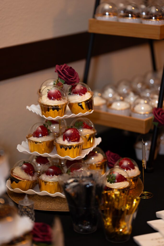red strawberry topped cupcakes at wedding dessert table