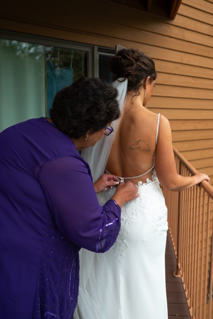 bride getting buttoned into dress