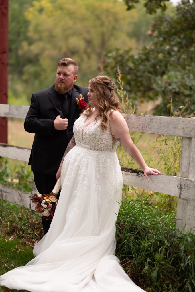 bride and groom posing along fence at Almquist farm in Hastings, MN